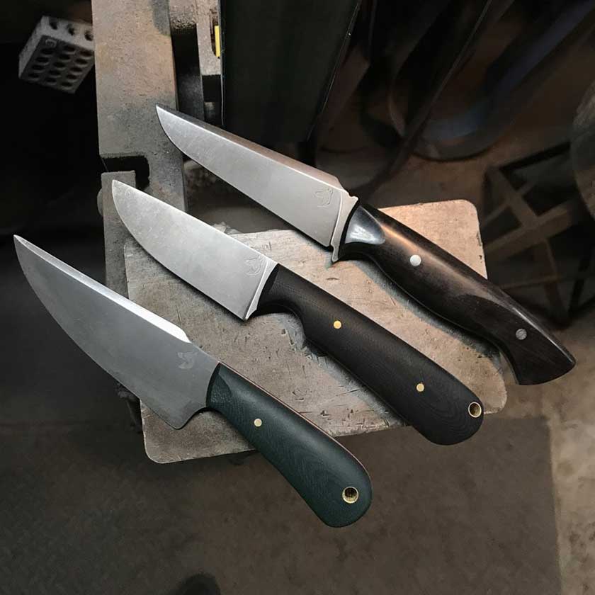 Three knives with black and green handles on a work platen surface